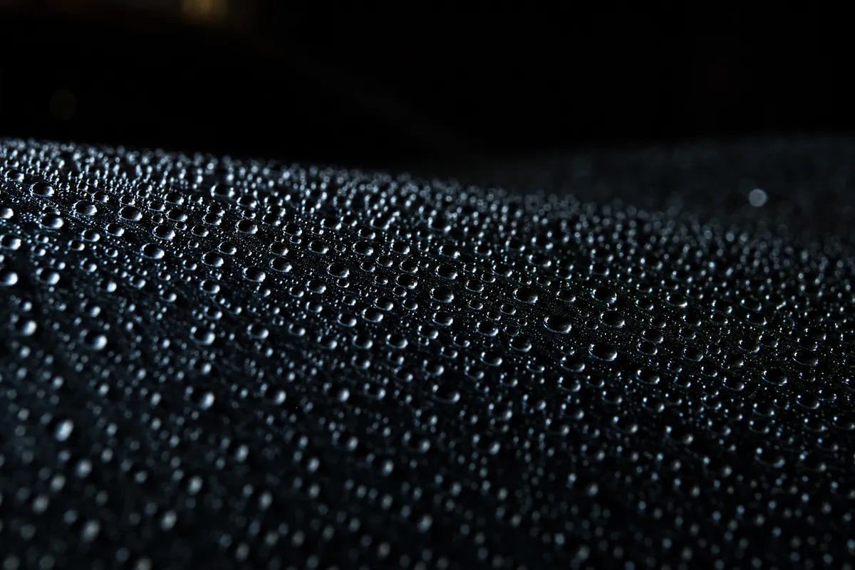Tight water beads standing on a ceramic-coated windshield at night