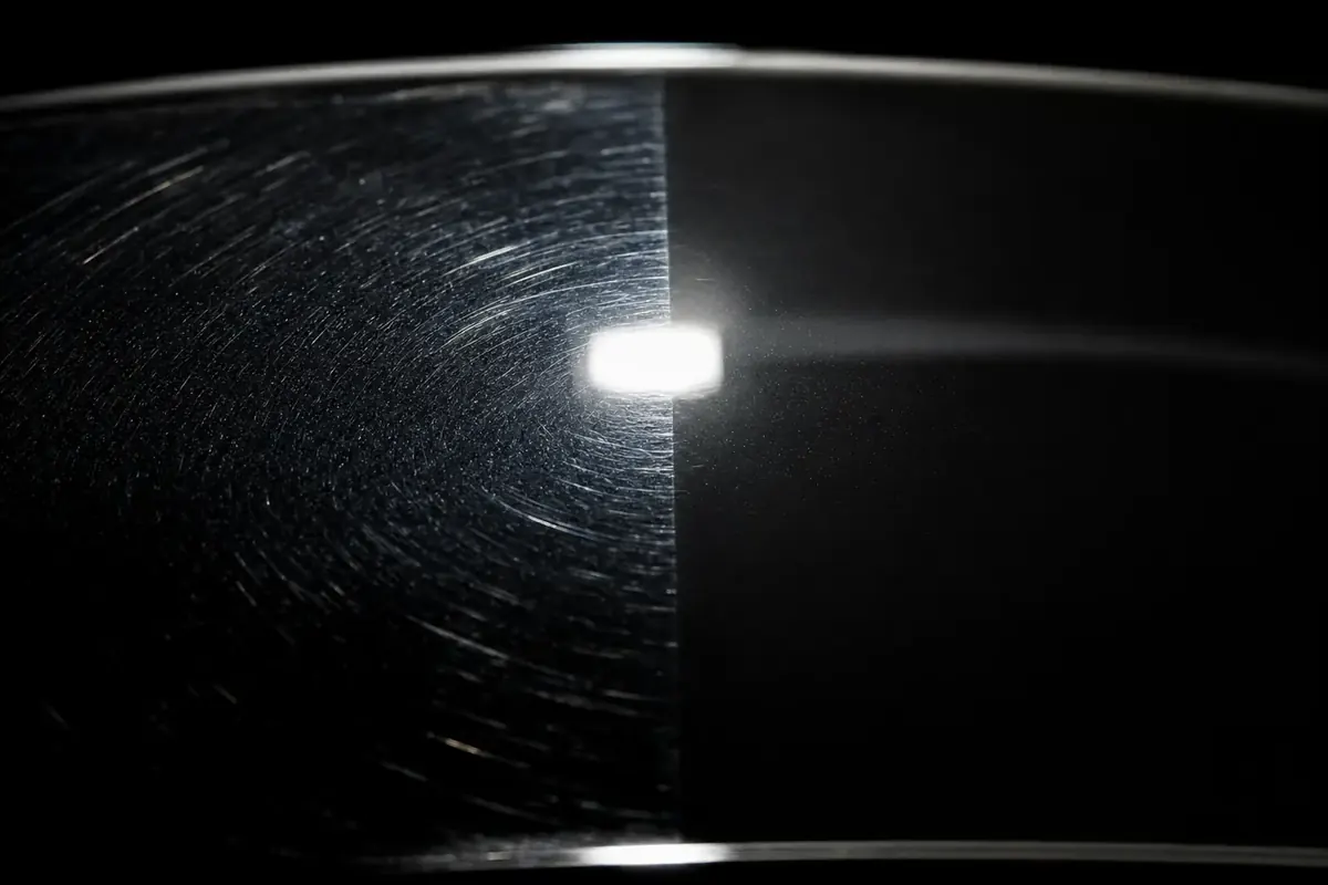 Macro of dark paint under inspection light, swirled on one side and corrected on the other
